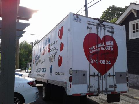 Two Small Men With Big Hearts Truck parckecked, loading the truck with a customers item in Downtown Vancouver, BC