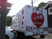 Two Small Men With Big Hearts Truck parckecked, loading the truck with a customers item in Downtown Vancouver, BC